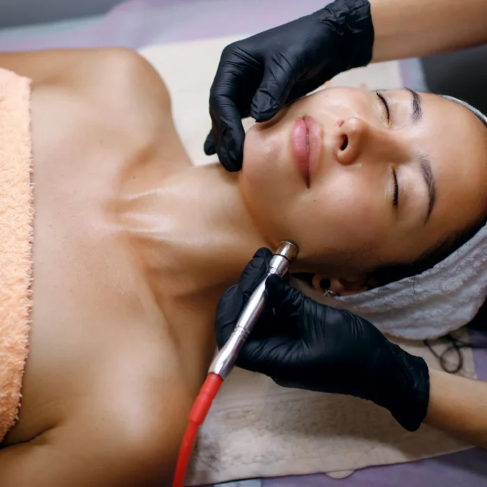 A professional female cosmetologist perform a hydrafacial procedure in a cosmetology clinic. The doctor cleans the pores of the face with a vacuum. Rejuvenation and hydration in the spa